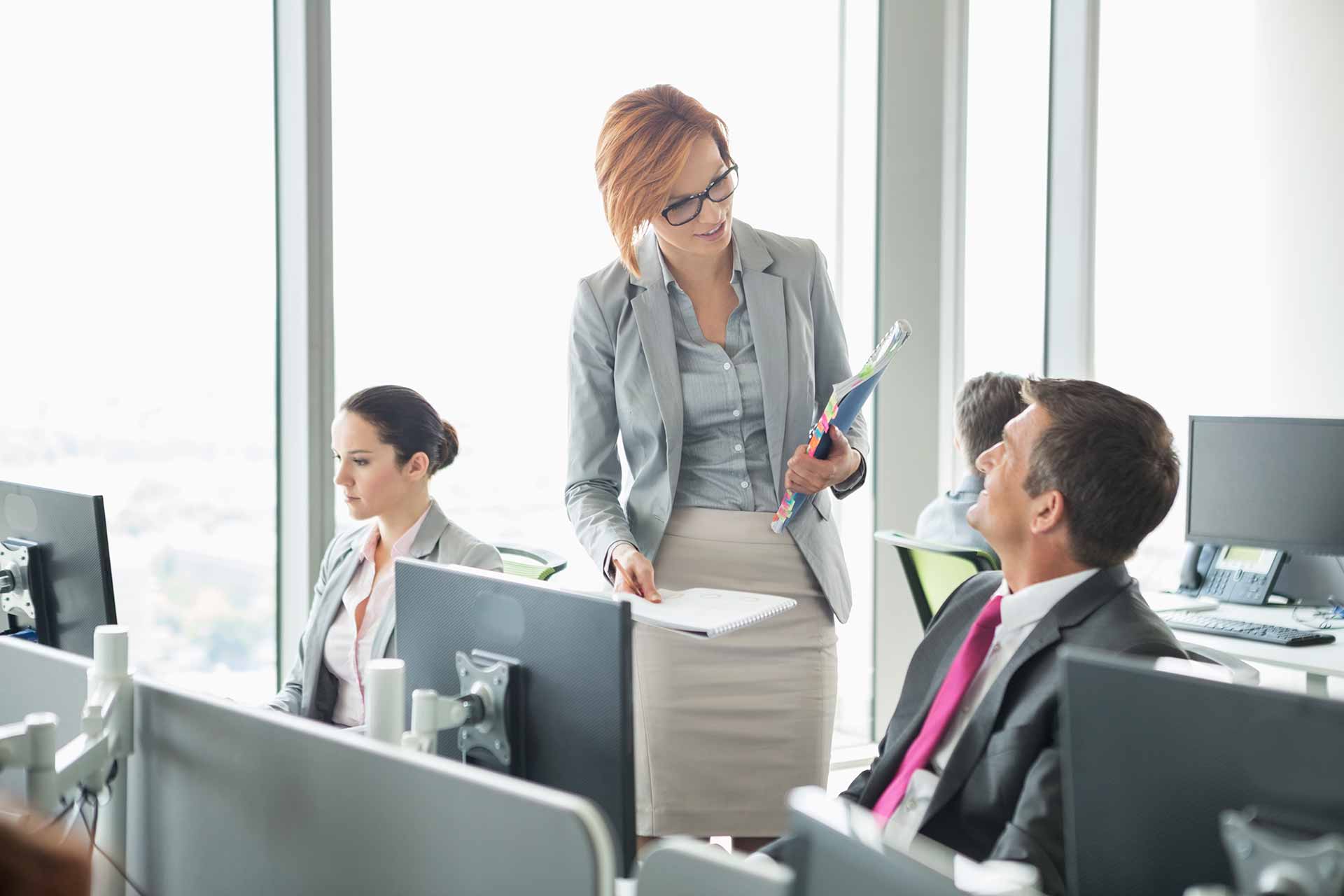 Executive chats with staff member at busy desk