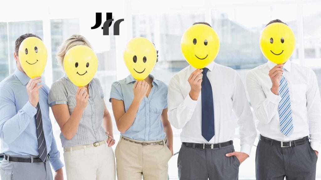 image of 5 people in dress shirts and slacks holding yellow smiley face balloons in front of their faces