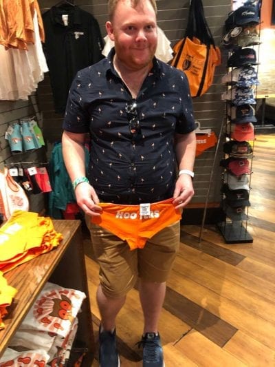 image of man holding orange swimsuit with word HOOTERS on the back