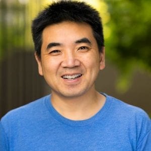 headshot of Zoom CEO Eric Yuan, smiling with a blue t-shirt