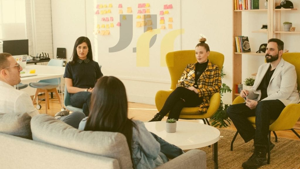 image of people meeting in a creative office, seated in a circle on comfortable chairs and couch